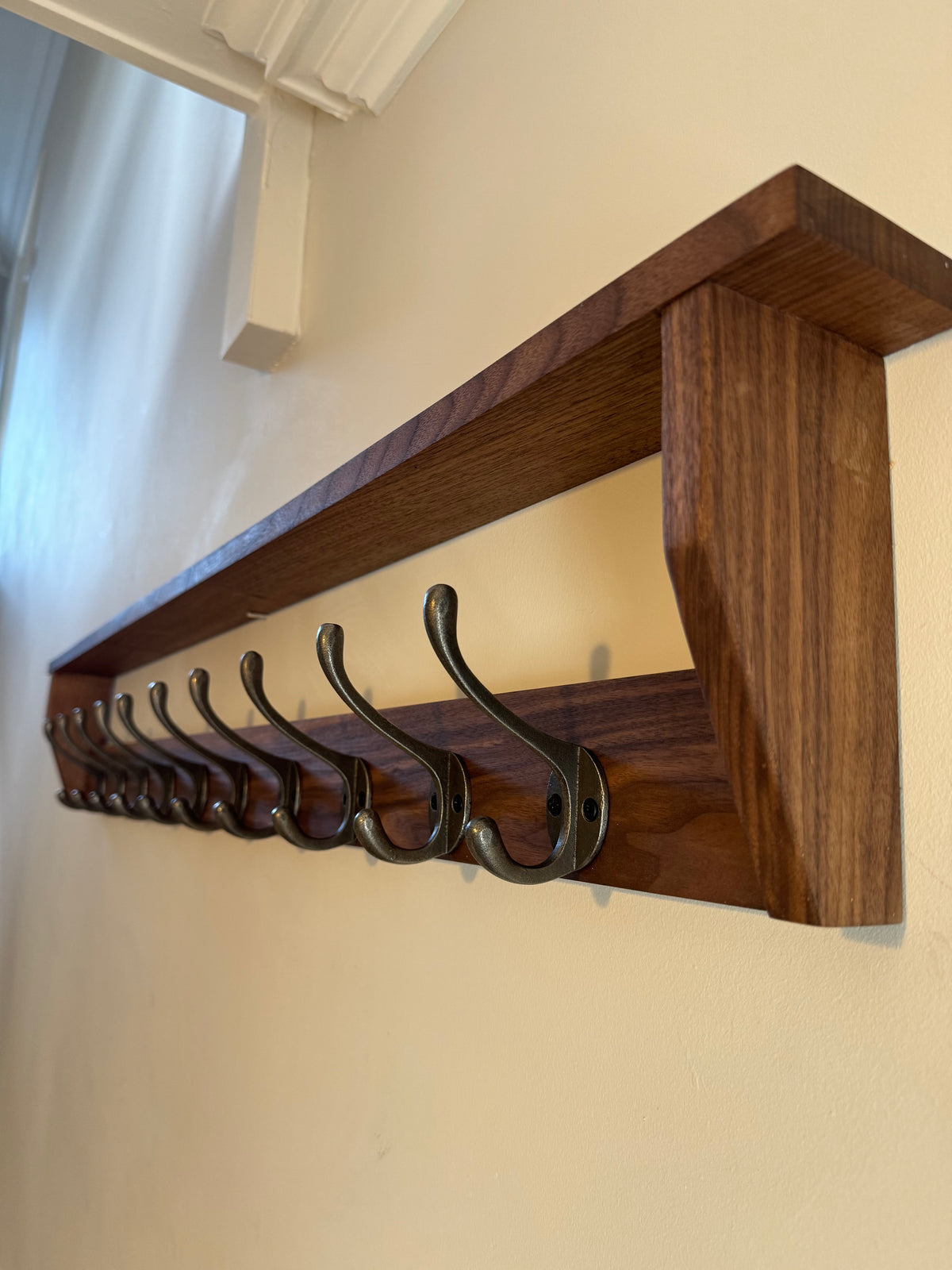 Handmade solid dark American walnut wooden coat rack with multiple cast iron hooks and a shelf, sanded and oiled for a smooth finish.